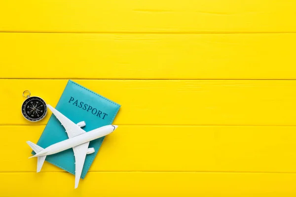 Modelo de avião com passaporte e bússola em mesa de madeira amarela — Fotografia de Stock