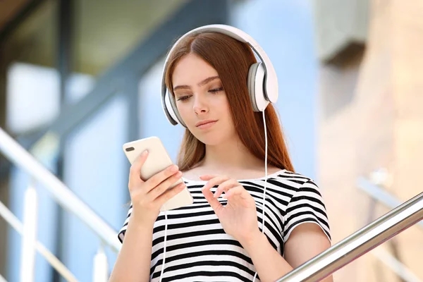 Mujer hermosa joven con auriculares y teléfono inteligente — Foto de Stock