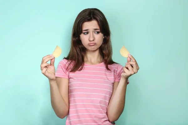 Молодая женщина с картофельными чипсами на фоне мяты — стоковое фото