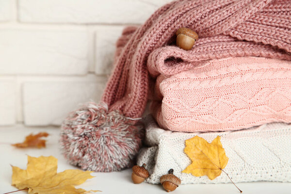 Stack of folded sweaters with scarf, acorns and autumn leafs on 