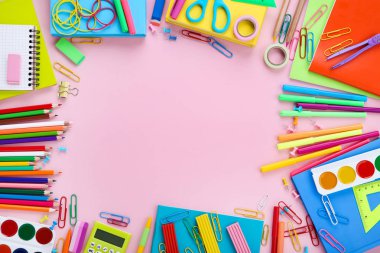 Pembe arka planda farklı okul malzemeleri.