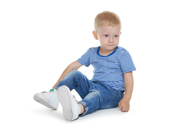 Маленький мальчик в модной одежде сидит на белом фоне — стоковое фото