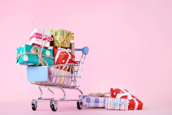 Kis bevásárlókosár díszdobozok a rózsaszín háttér — Stock Fotó