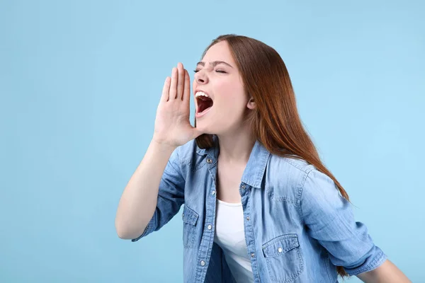 Ung vacker kvinna skriker på blå bakgrund — Stockfoto