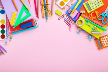 Pembe arka planda farklı okul malzemeleri.