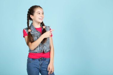 Mavi arka planda parmak gösteren güzel genç kız