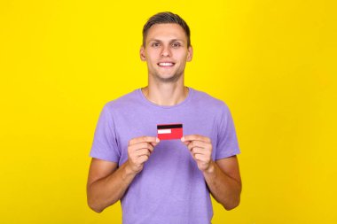 Sarı arka planda kredi kartı tutan genç adam