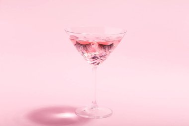 Pembe arka planda kirpikli camkokteyl. Minimalizm 