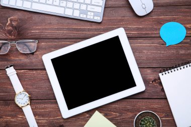 Kahverengi ağaçlık üzerinde ofis malzemeleri ile tablet ve bilgisayar klavyesi