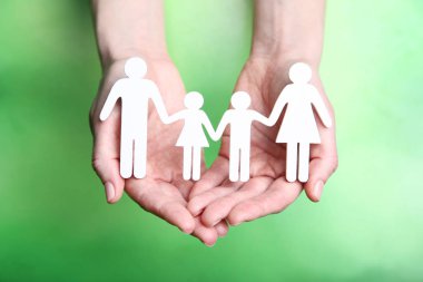 Yeşil arka planda kadın ellerde aile figürleri