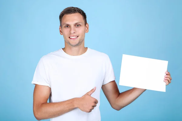 Junger Mann mit blankem Brett und Daumen nach oben auf blauem Hintergrund — Stockfoto