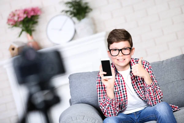 Jonge jongen met smartphone zittend op de Bank en records video — Stockfoto