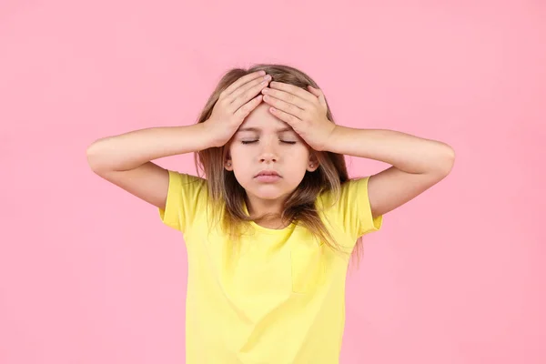 Liten flicka som har huvudvärk på rosa bakgrund — Stockfoto