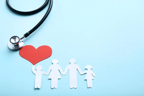 Figury rodzinne z czerwonym sercem i stetoskopem na niebieskim tle — Zdjęcie stockowe
