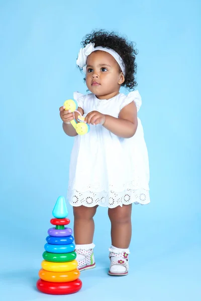 Menina bonita com brinquedo arco-íris no fundo azul — Fotografia de Stock