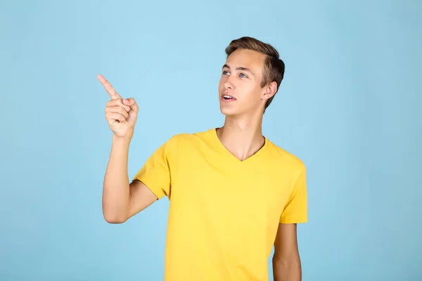 Porträtt av ung man i gul t-shirt på blå bakgrund — Stockfoto