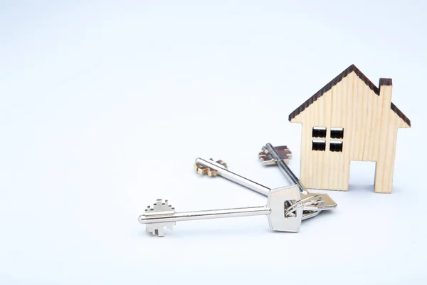 Stříbrné klíče s dřevěným domem na šedém pozadí — Stock fotografie