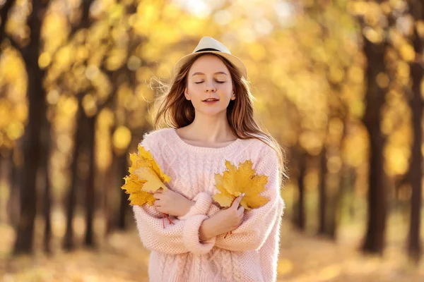 Młoda piękna dziewczyna z kapeluszem i klon liści w jesiennym parku — Zdjęcie stockowe