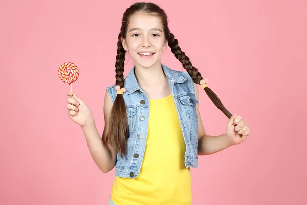 Beautiful young girl with sweet lollipop on pink background — Stock Photo, Image