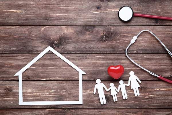 Familienfiguren mit rotem Herz, Papierhaus und Stethoskop auf br — Stockfoto