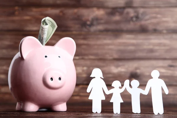 Figuras de família com piggybank na mesa de madeira marrom — Fotografia de Stock