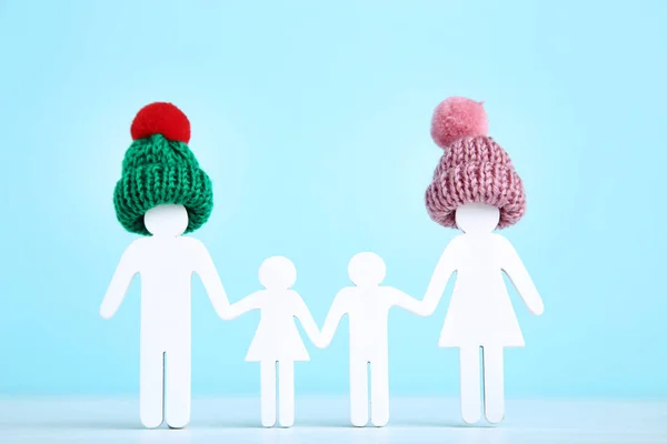 Wooden family figures in small hats on blue background