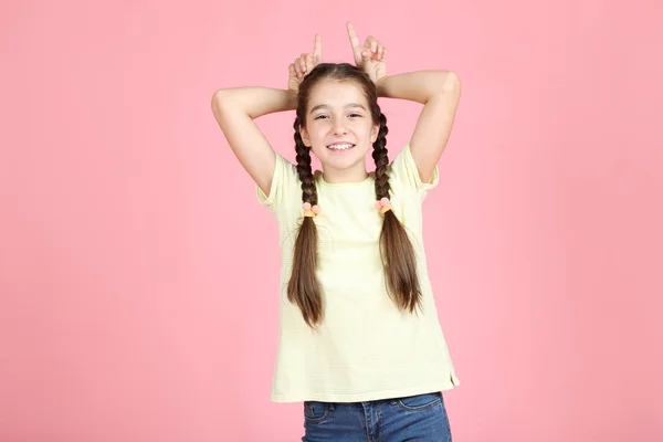 Mooi jong meisje toont oren door handen op roze achtergrond — Stockfoto