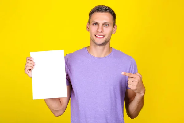 Junger Mann mit leerem Brett auf gelbem Hintergrund — Stockfoto
