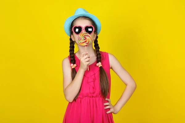 Beautiful young girl with sweet lollipop on yellow background — Stock Photo, Image