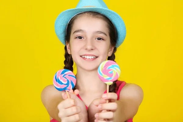 Bella ragazza con dolci lecca-lecca su sfondo giallo — Foto Stock