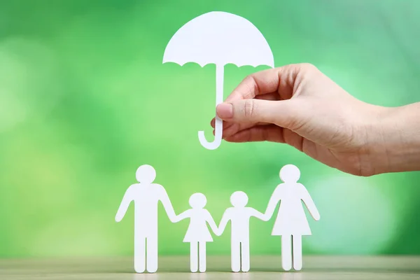 Figuras de família e mão feminina segurando guarda-chuva de papel em verde b — Fotografia de Stock