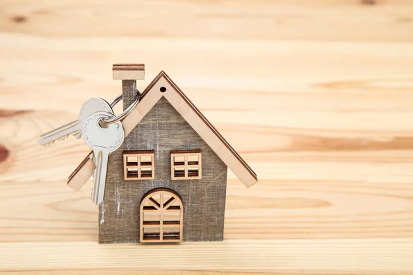 Silberne Schlüssel mit Haussymbol auf braunem Holztisch — Stockfoto
