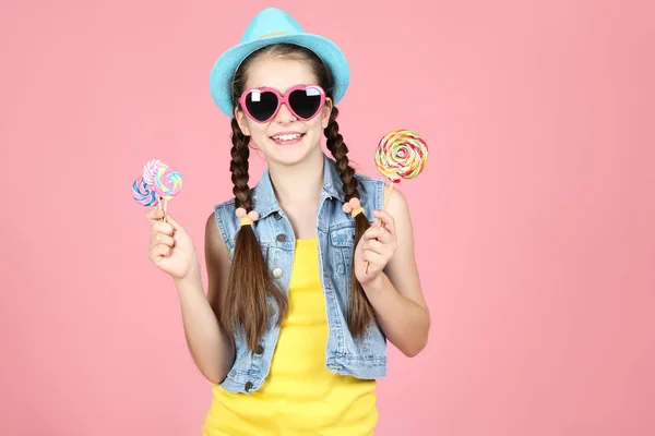 Menina bonita com pirulitos doces no fundo rosa — Fotografia de Stock