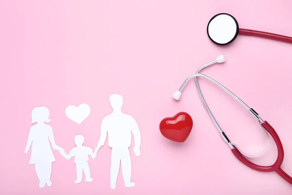 Figuras familiares con corazón rojo y estetoscopio sobre fondo rosa — Foto de Stock