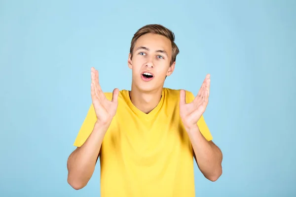 Portret van de jonge man in geel t-shirt op blauwe achtergrond — Stockfoto