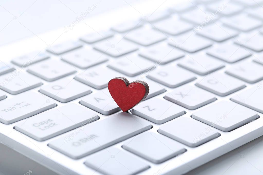 Computer keyboard with red heart on white background