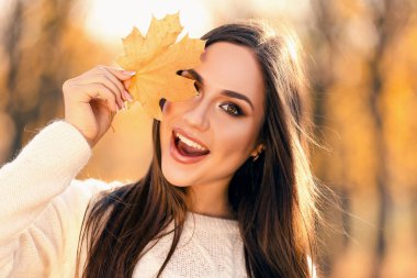 Sonbahar park akçaağaç yaprağı tutan güzel kadın