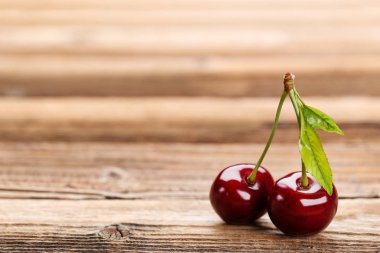 Kahverengi ahşap masa üzerinde yapraklar ile Tatlı kiraz