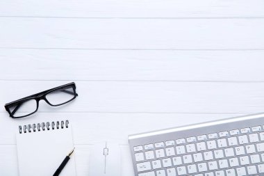 Beyaz ahşap ofis malzemeleri ve gözlük ile bilgisayar klavyesi