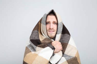 Genç adam gri arka plan üzerinde ekose ile hasta hissediyor