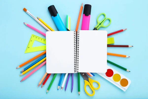 Diferentes materiais escolares e folha de papel em branco sobre backg azul — Fotografia de Stock