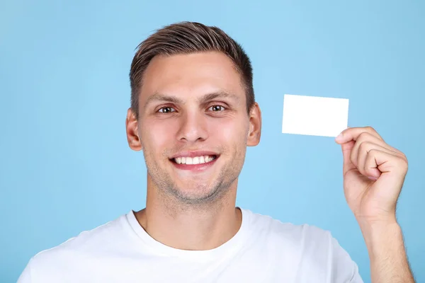 Молодий чоловік з порожньою візитною карткою на синьому фоні — стокове фото