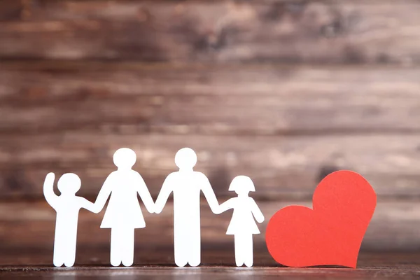 Rodinné postavy s červeným srdcem na hnědém dřevěném stole — Stock fotografie