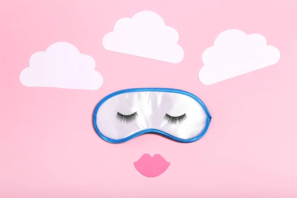 Sleeping mask with paper clouds and eyelashes on pink background