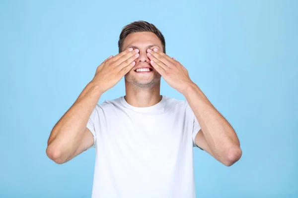 Portrait of young man with closed eyes by hands on blue background