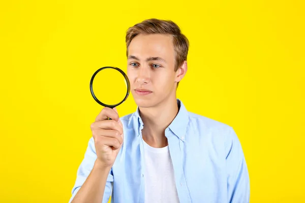 Jonge man met vergrootglas op gele achtergrond — Stockfoto