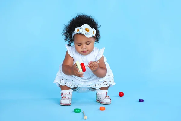 Menina bonita com brinquedos de plástico no fundo azul — Fotografia de Stock