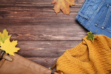 Kahverengi kot pantolon, deri çanta ve akçaağaç yaprağı ile örme kazak