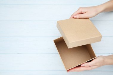 Kadın elleri ahşap masa üzerinde hediye kutusu açma