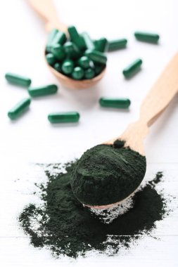 Spirulina toz ve kapsüller ahşap masada kaşık